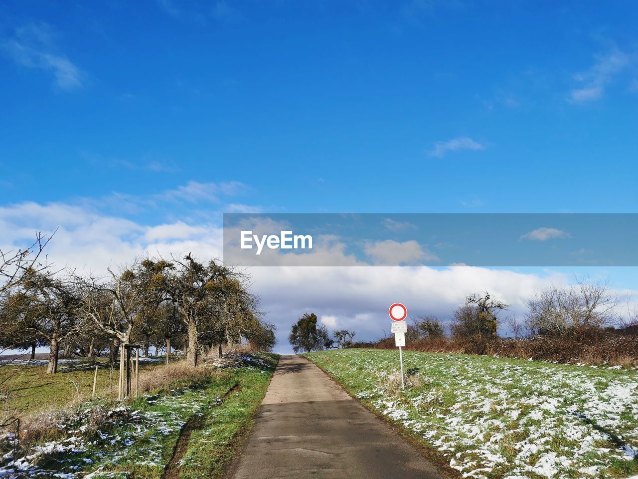 ROAD AMIDST FIELD AGAINST BLUE SKY