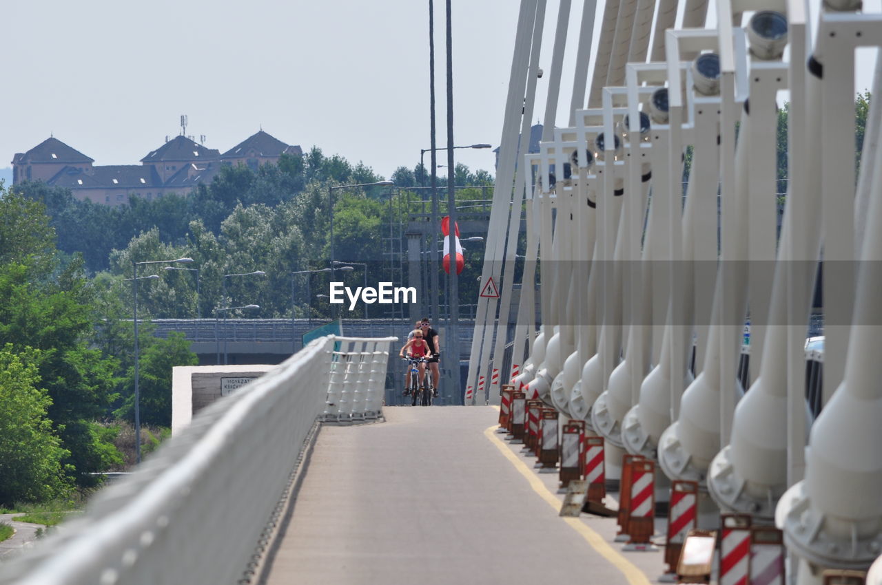 Man and boy riding bicycle on footpath of bridge