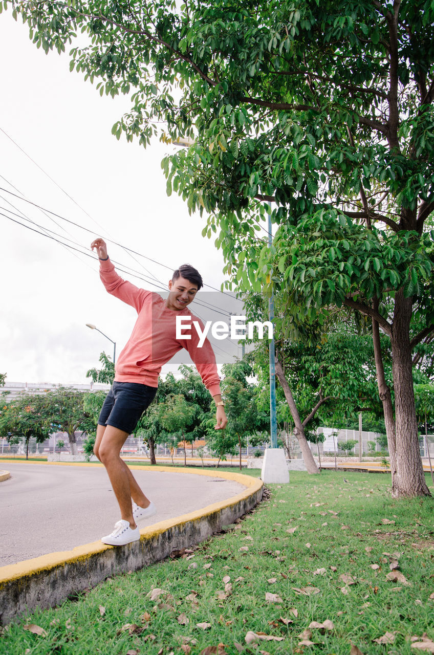 Full length of man balancing by empty road against sky