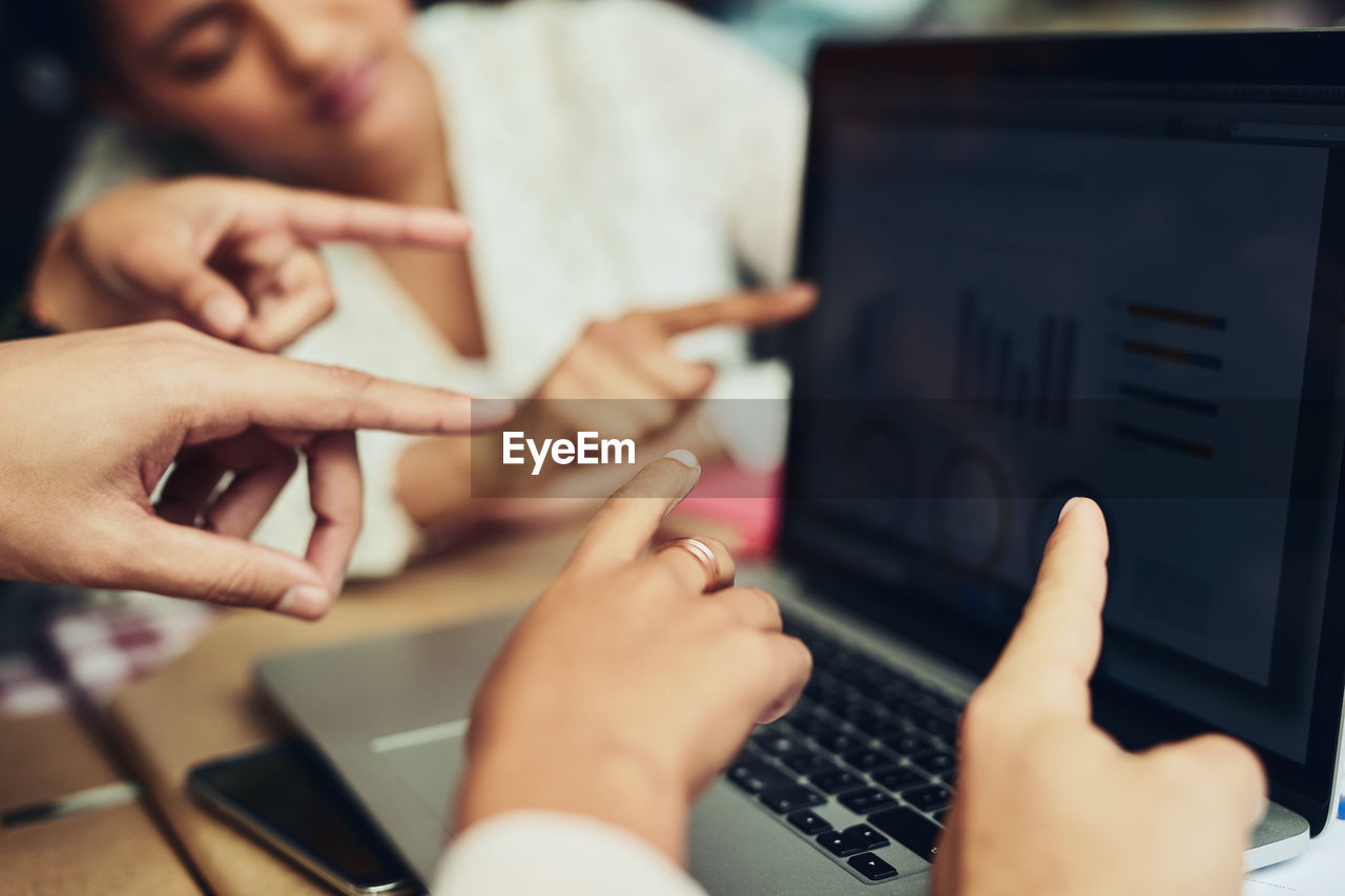 cropped hands of woman using laptop on table