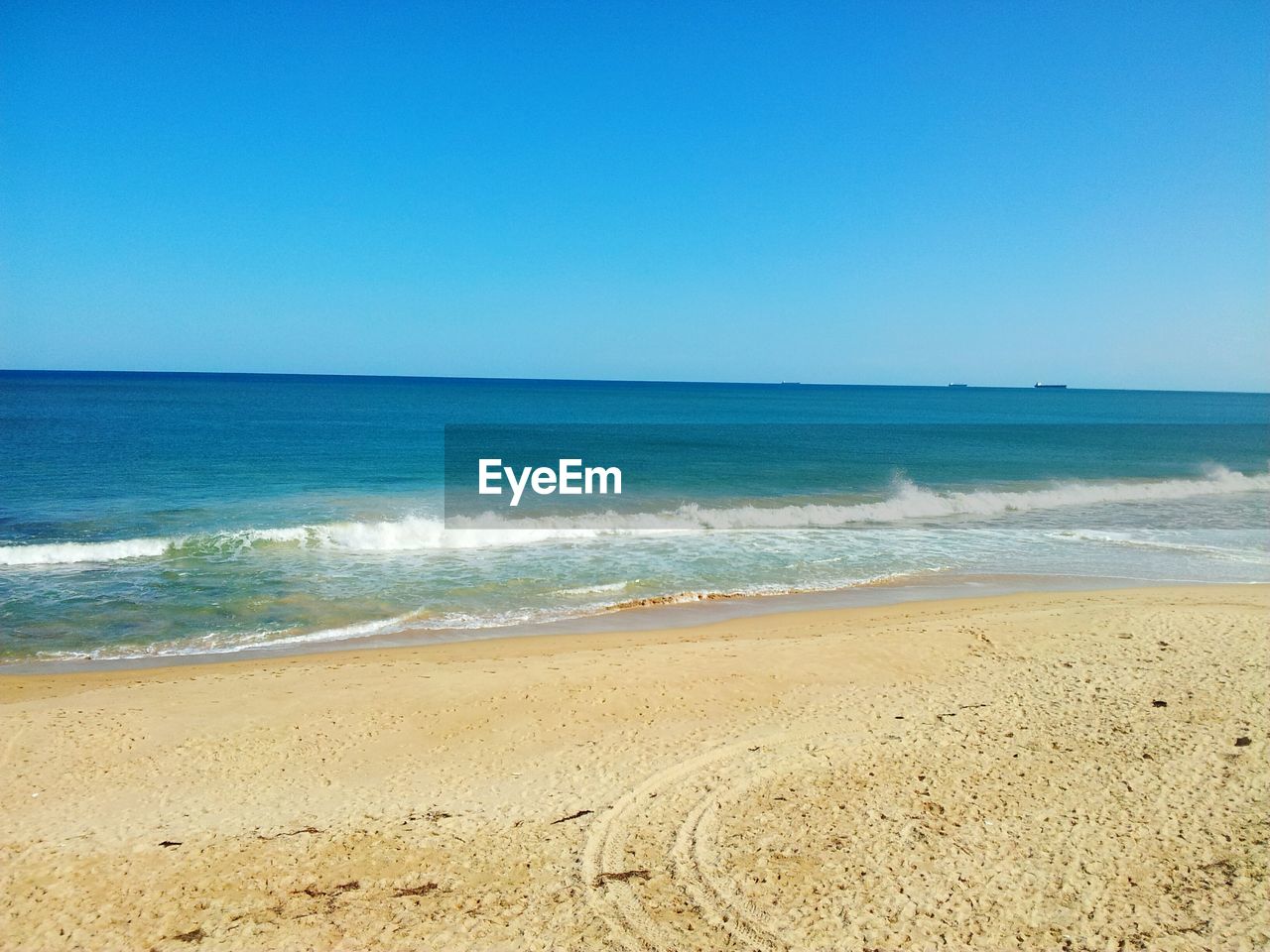 Scenic view of beach against clear blue sky