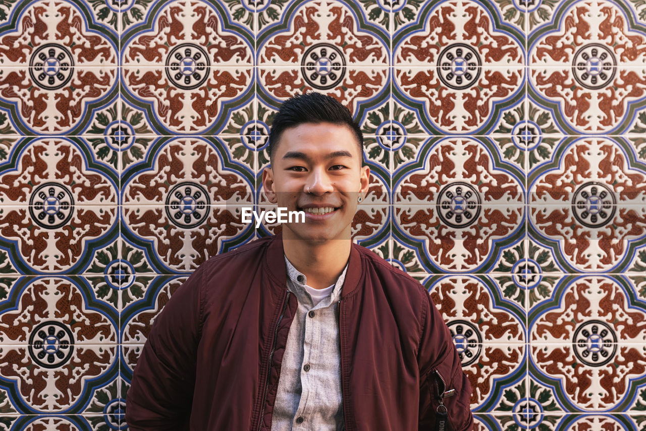 Portrait of young man standing against wall