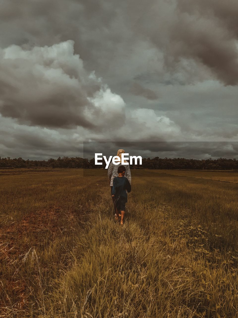 Rear view of man standing on field against sky