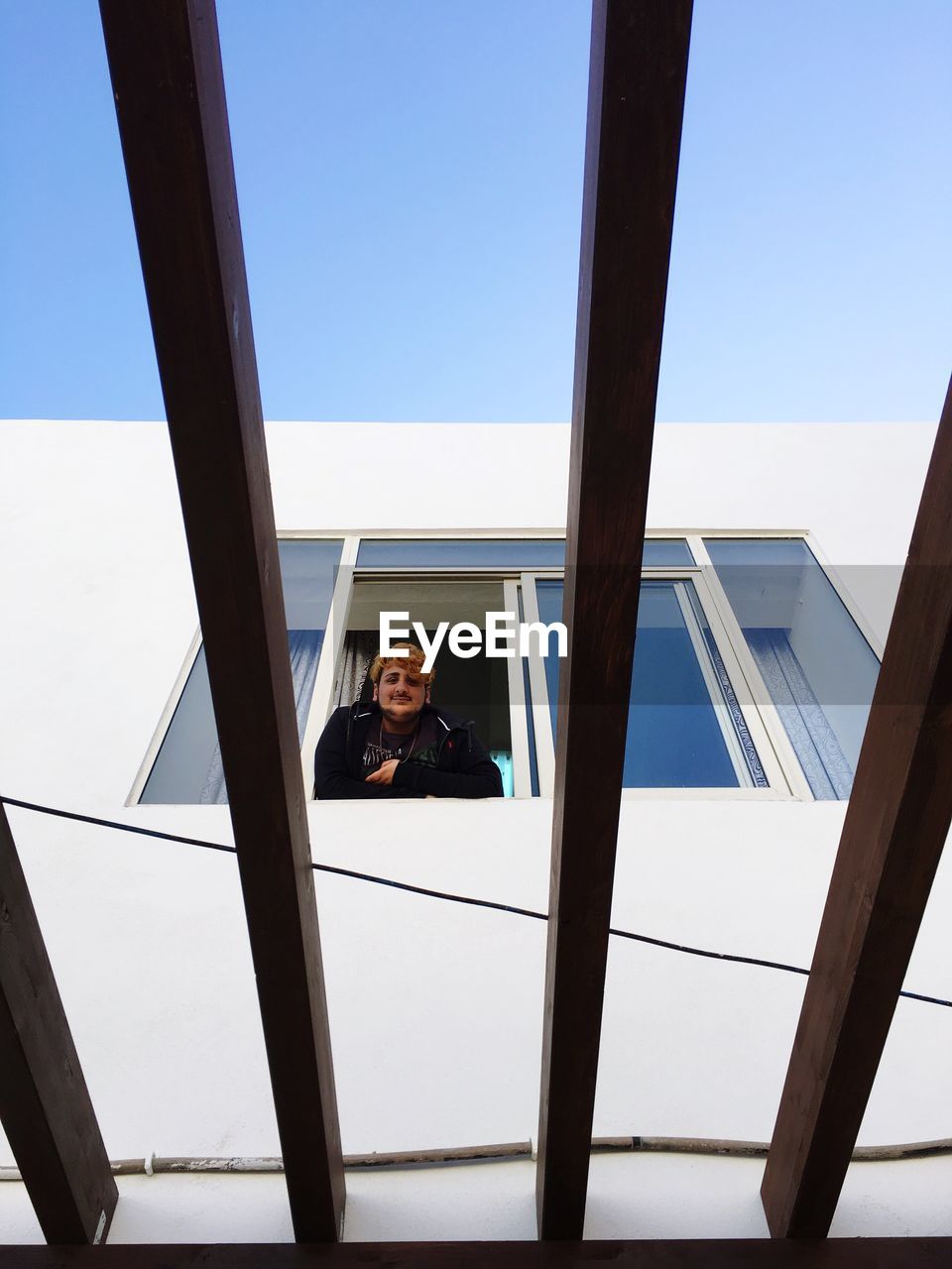 BOY BY WINDOW AGAINST SKY