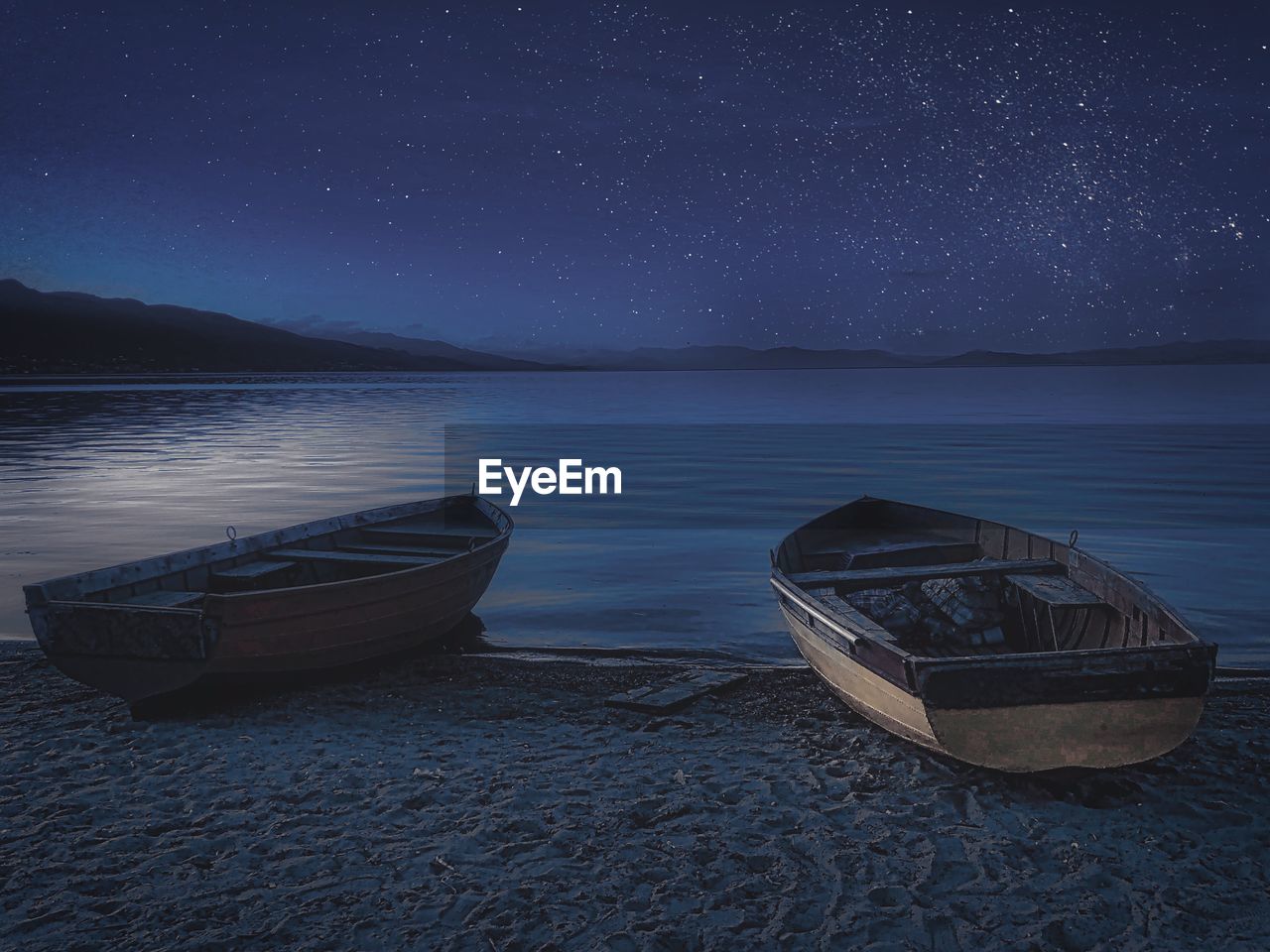 Boat moored on beach against sky at night