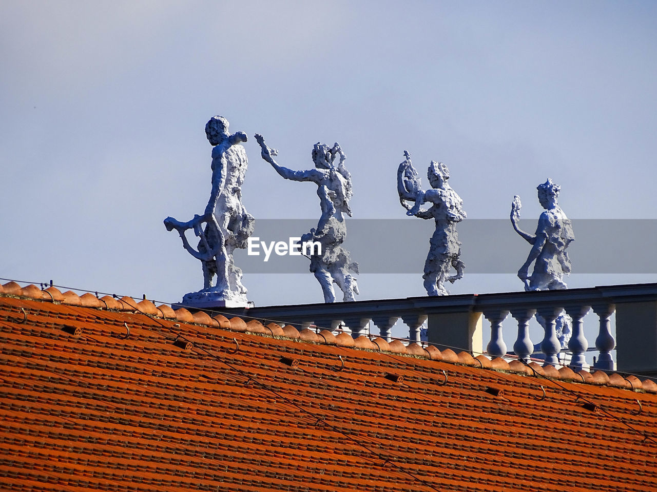 Low angle view of sculpture on roof against sky