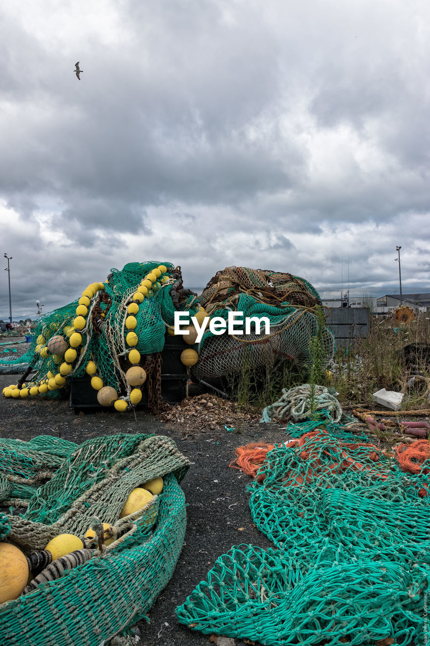 Fishing nets at harbor against cloudy sky