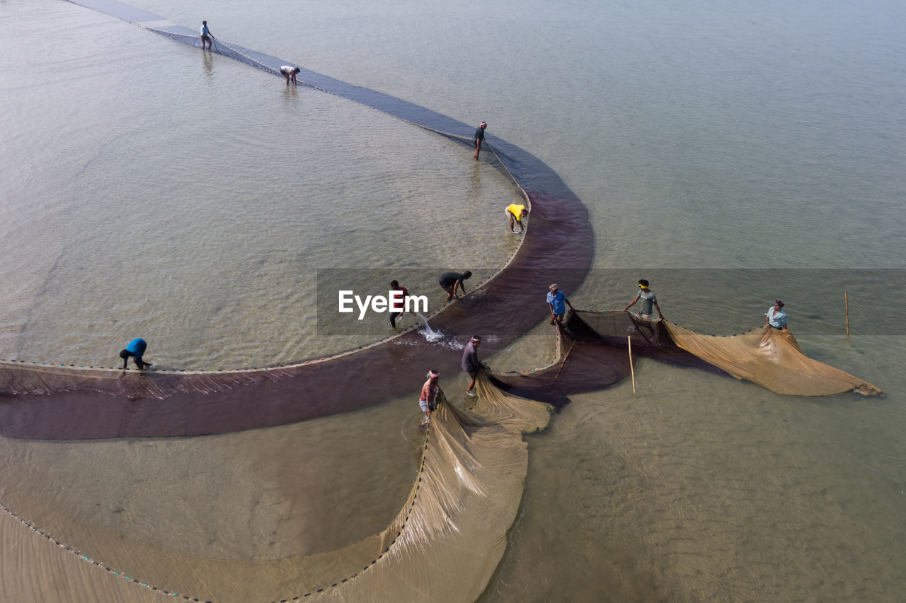 PEOPLE ON BEACH AGAINST SEA