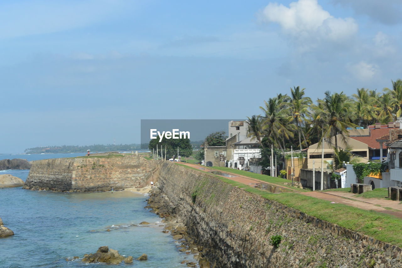 Scenic view of sea by buildings against sky