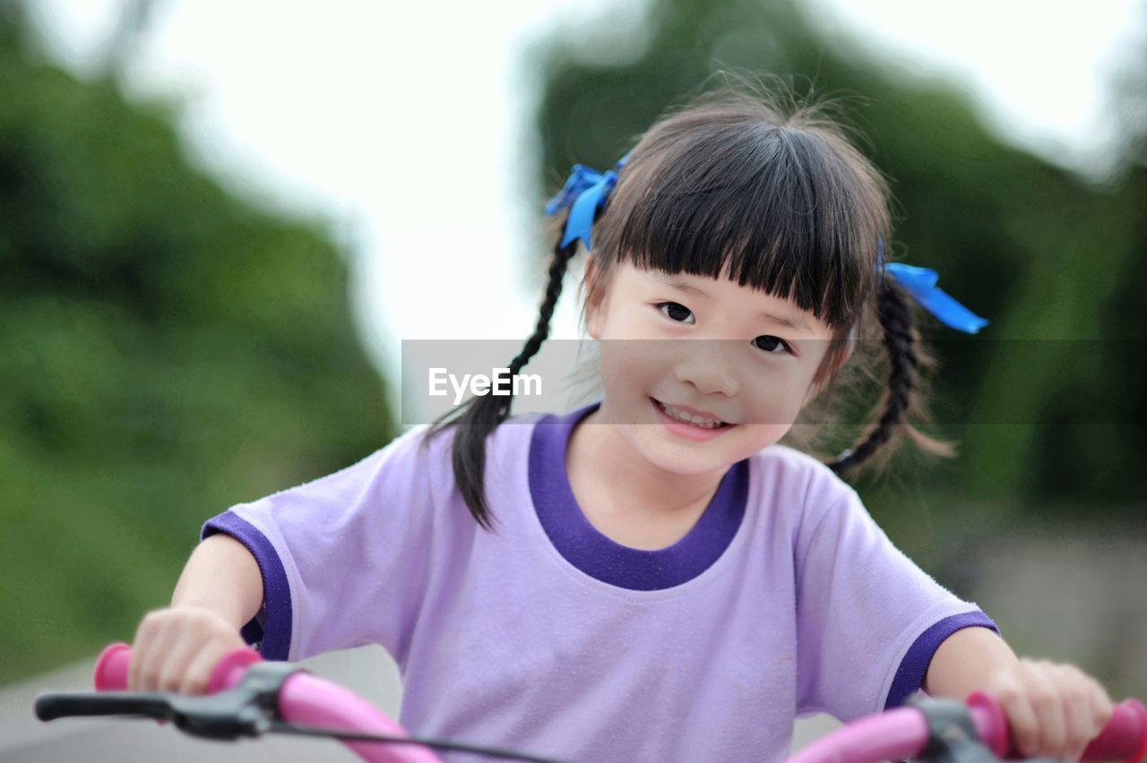 Portrait of smiling girl riding bicycle outdoors