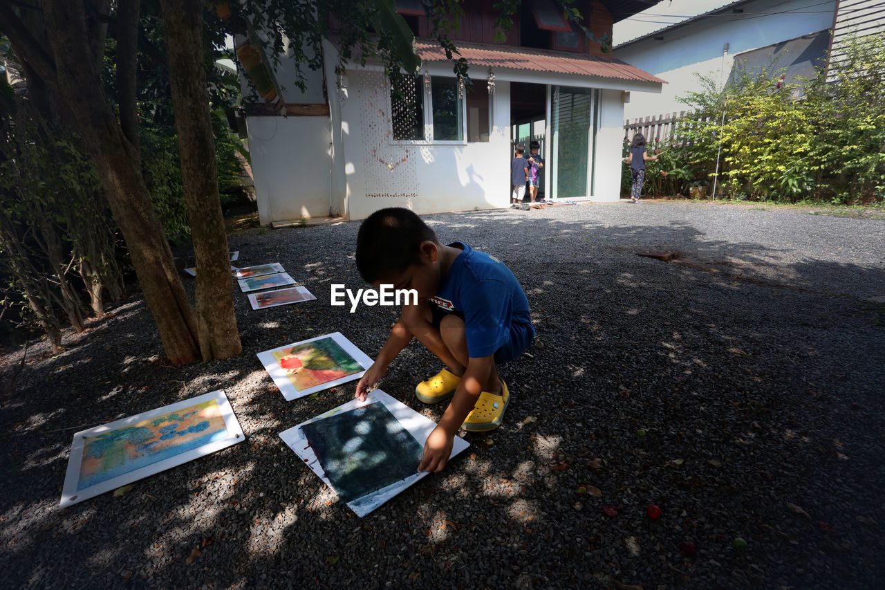 REAR VIEW OF BOY HOLDING UMBRELLA ON FLOOR