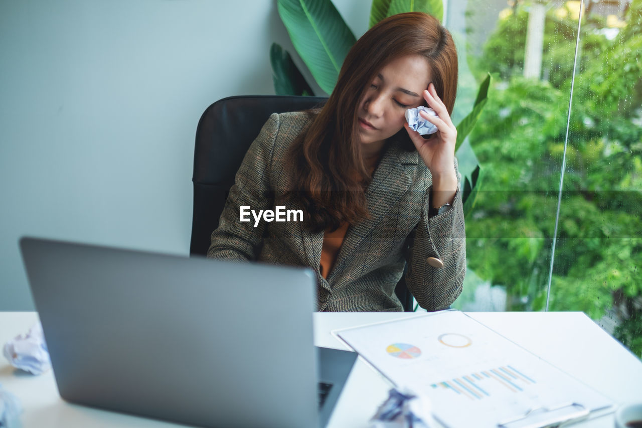 young businesswoman using laptop while sitting at office