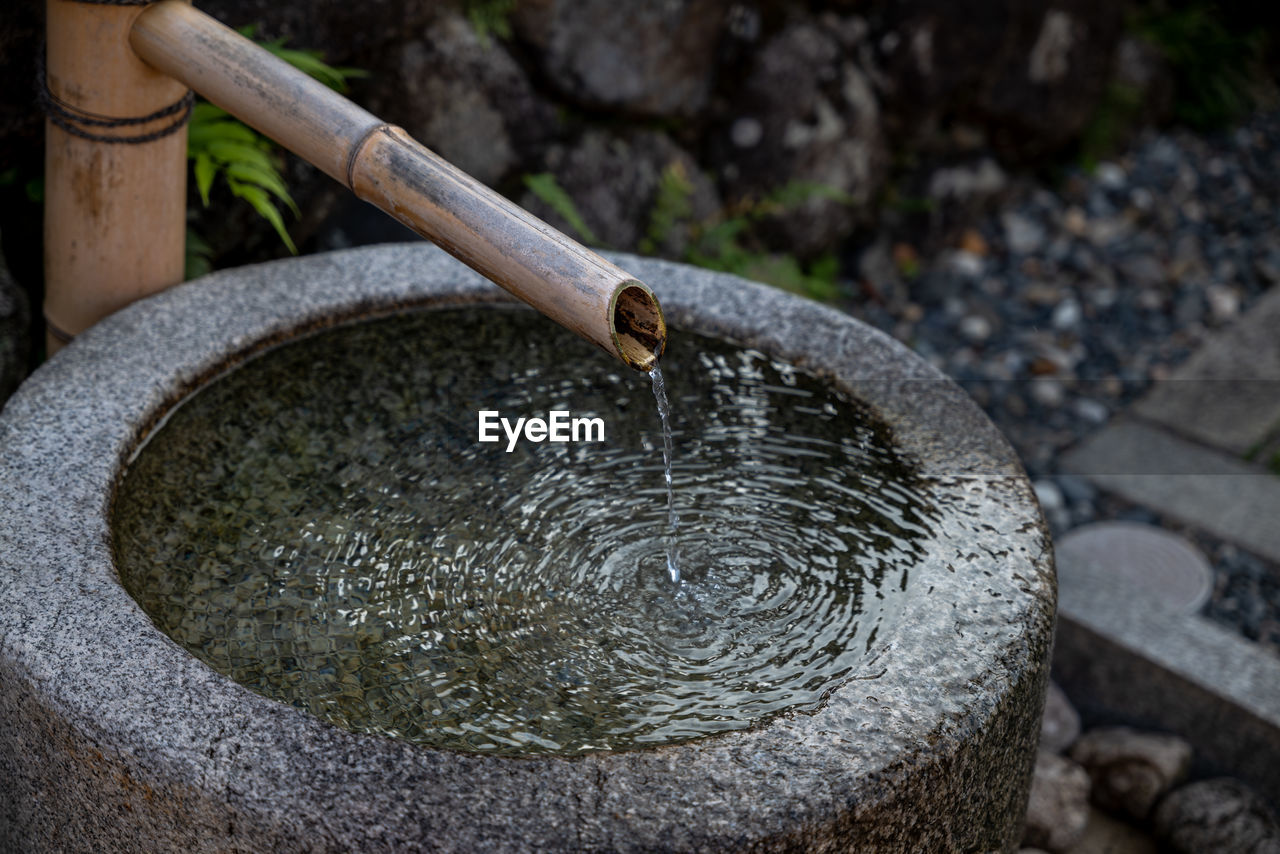 water, soil, nature, fountain, water feature, day, no people, ladle, kitchen utensil, outdoors, close-up, drinking fountain, iron, motion, household equipment, high angle view, focus on foreground, food and drink, culture, japanese garden, stone material, stone