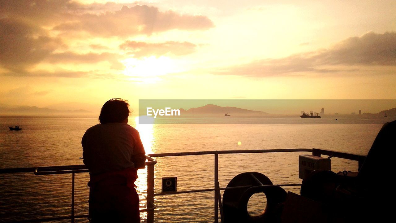 Rear view of man standing on yacht while looking at sea