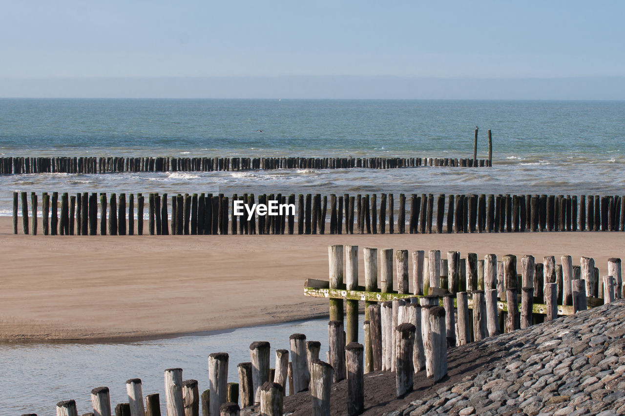 Wooden posts on beach against sky