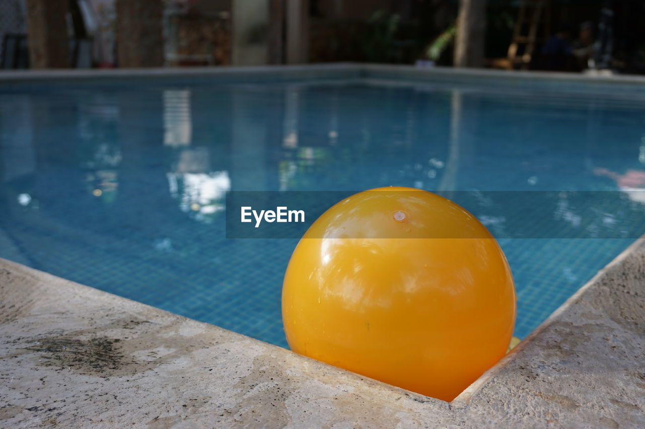 A yellow ball in the corner of a water pool