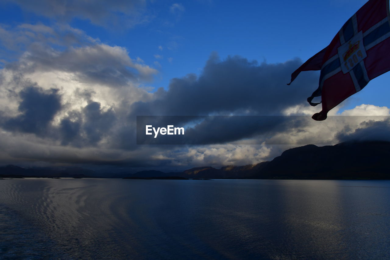 sky, water, cloud, reflection, sea, nature, environment, horizon, scenics - nature, flag, blue, beauty in nature, patriotism, mountain, tranquility, no people, ocean, flying, tranquil scene, outdoors, dusk, wind, day, transportation, landscape, travel, land, travel destinations