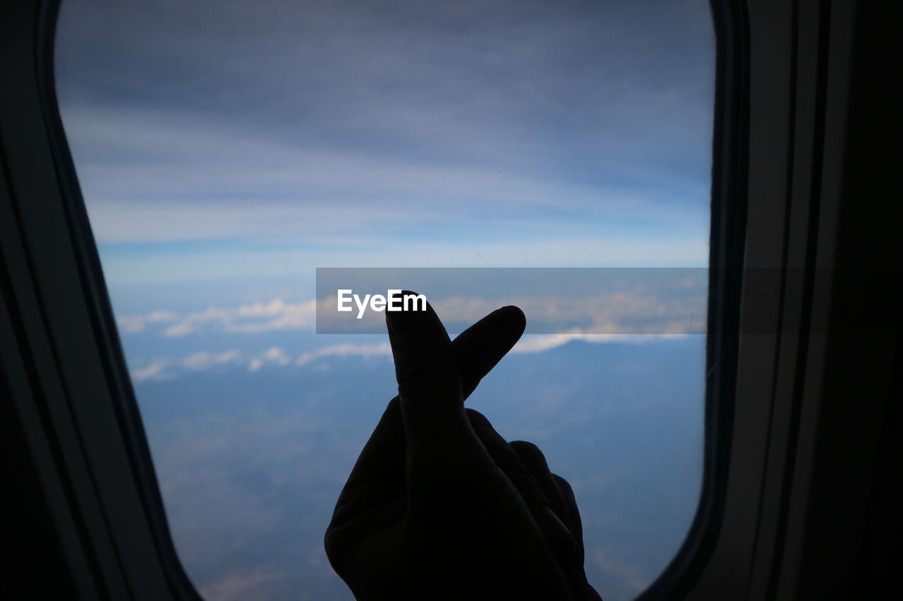 Silhouette hand gesturing by airplane window