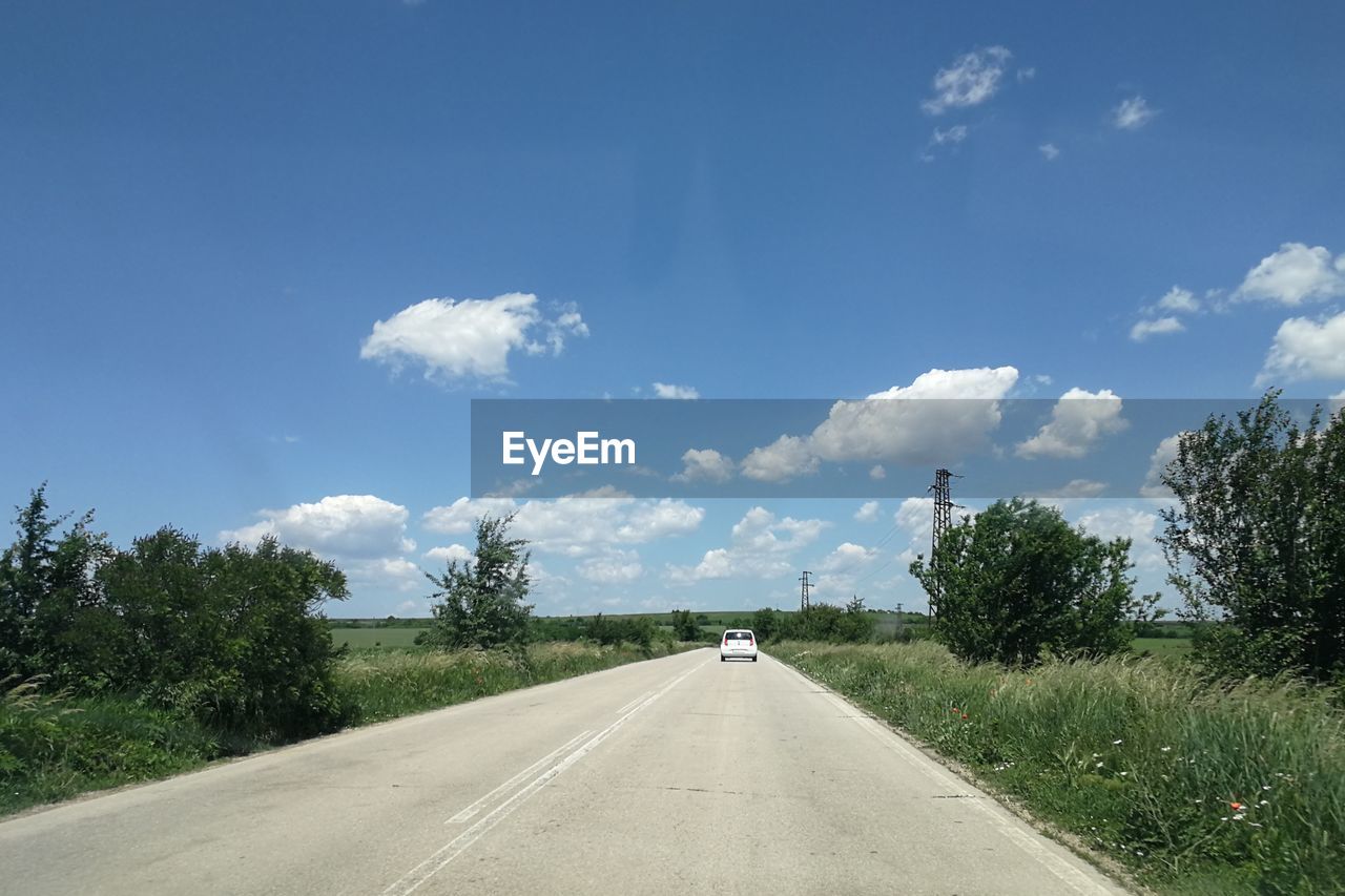 ROAD AMIDST PLANTS ON LAND AGAINST SKY