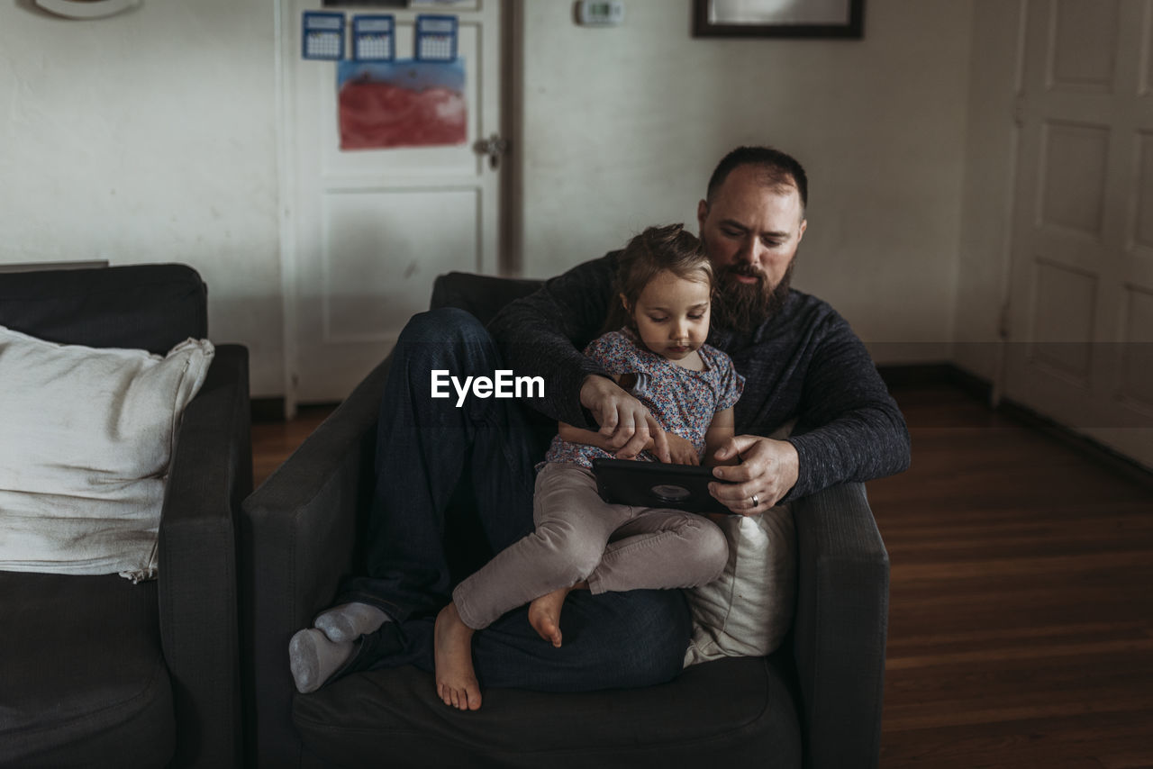 Dad and young daughter playing on tablet during isolation