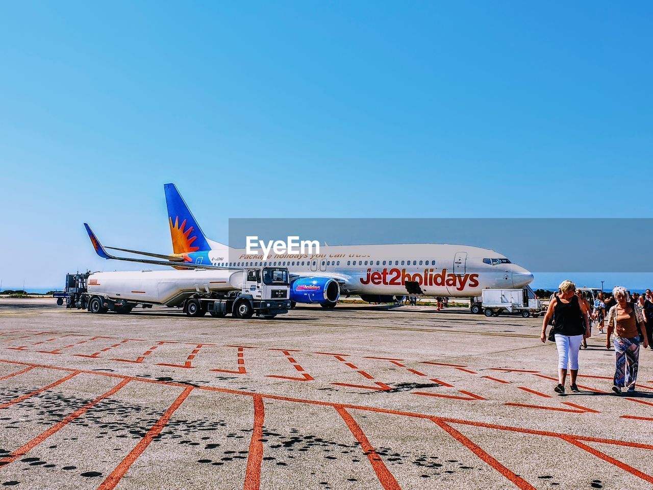 PEOPLE AT AIRPORT RUNWAY AGAINST SKY