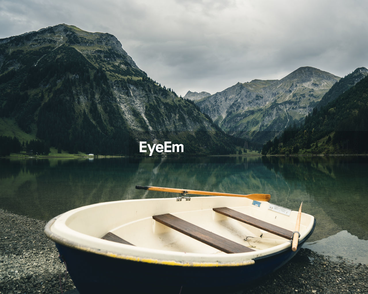 BOAT MOORED IN LAKE AGAINST SKY