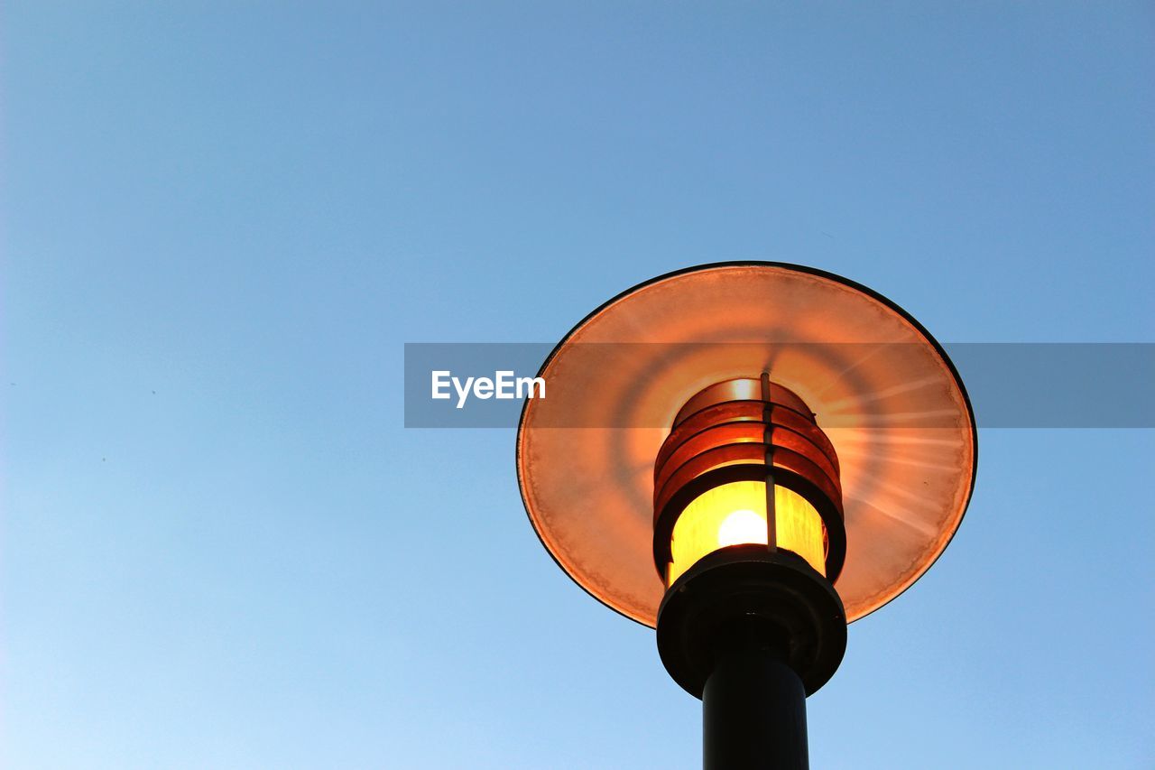 Low angle view of illuminated gas light against clear blue sky