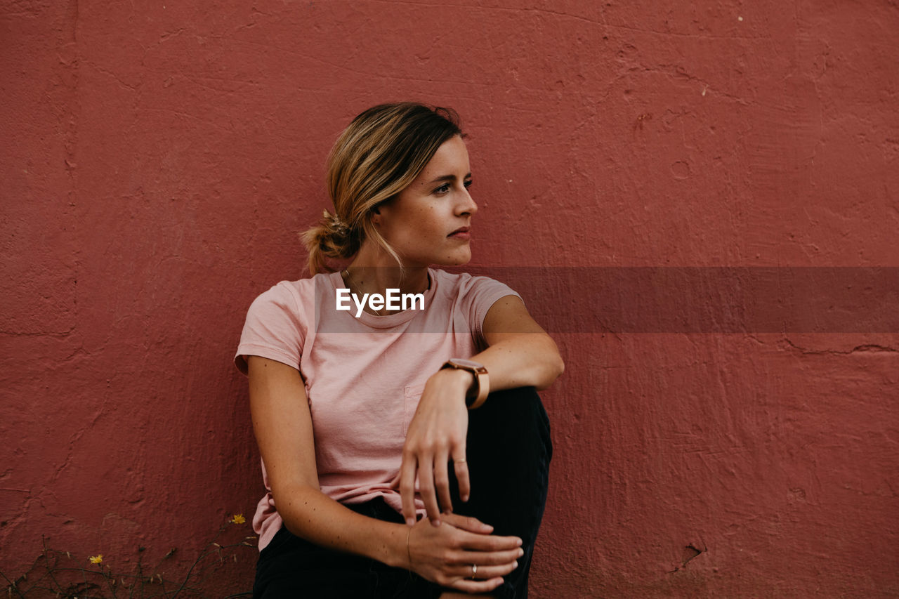 Woman looking away against wall