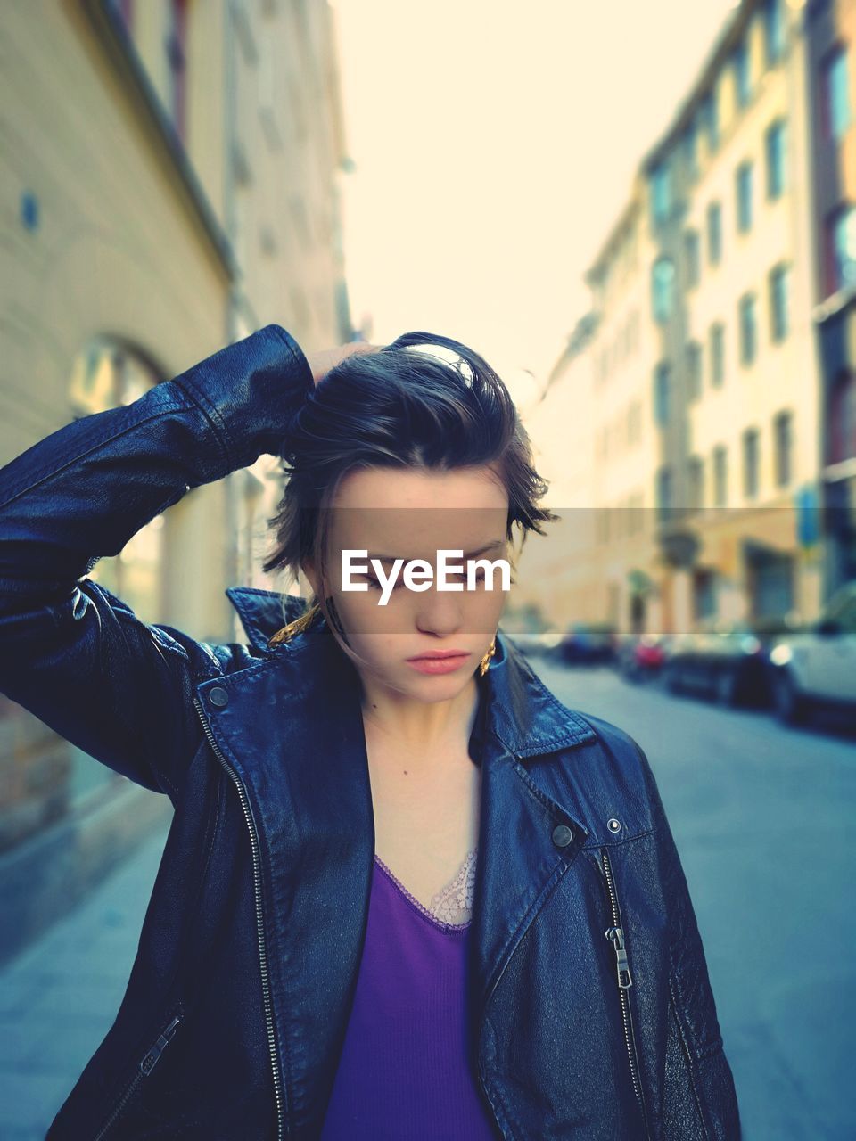 Beautiful young woman looking down with buildings in background