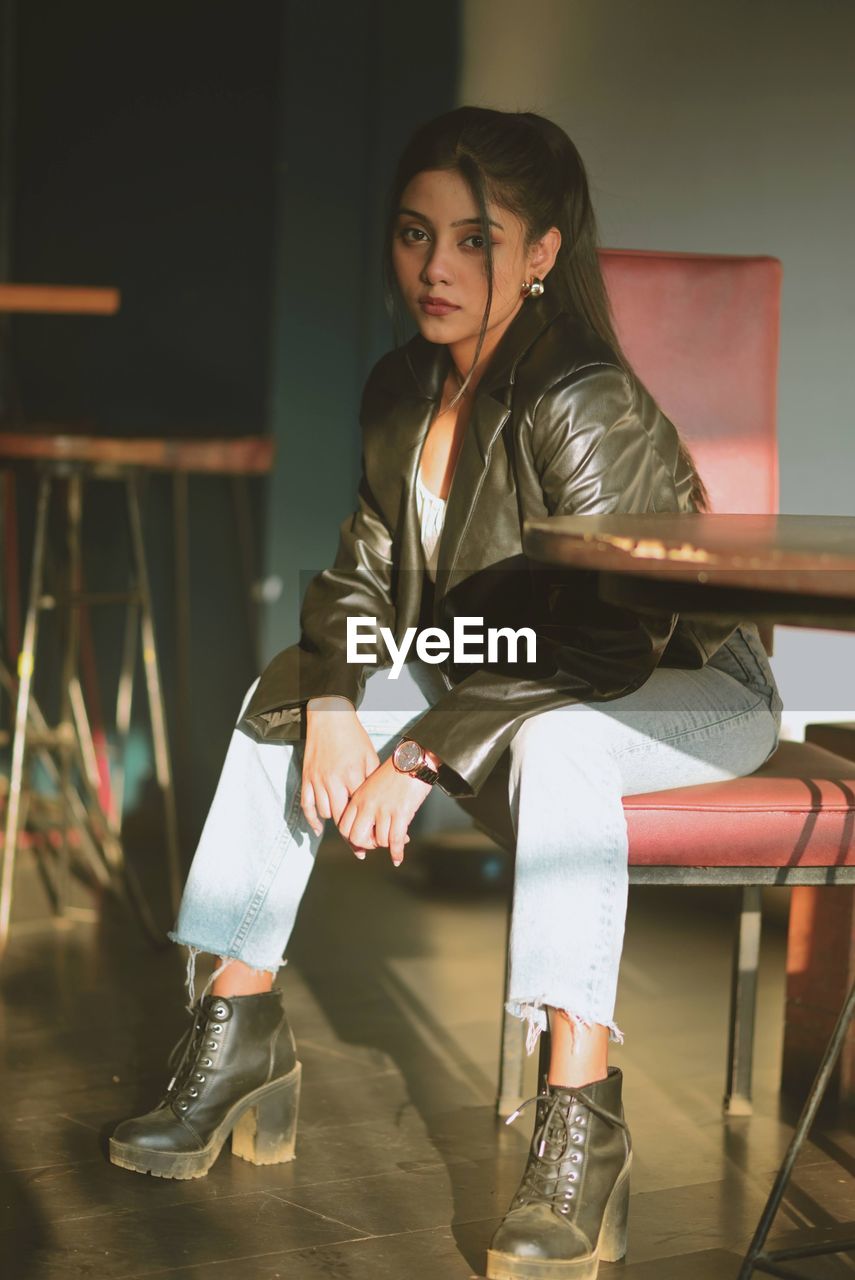 Full length of young woman sitting on chair