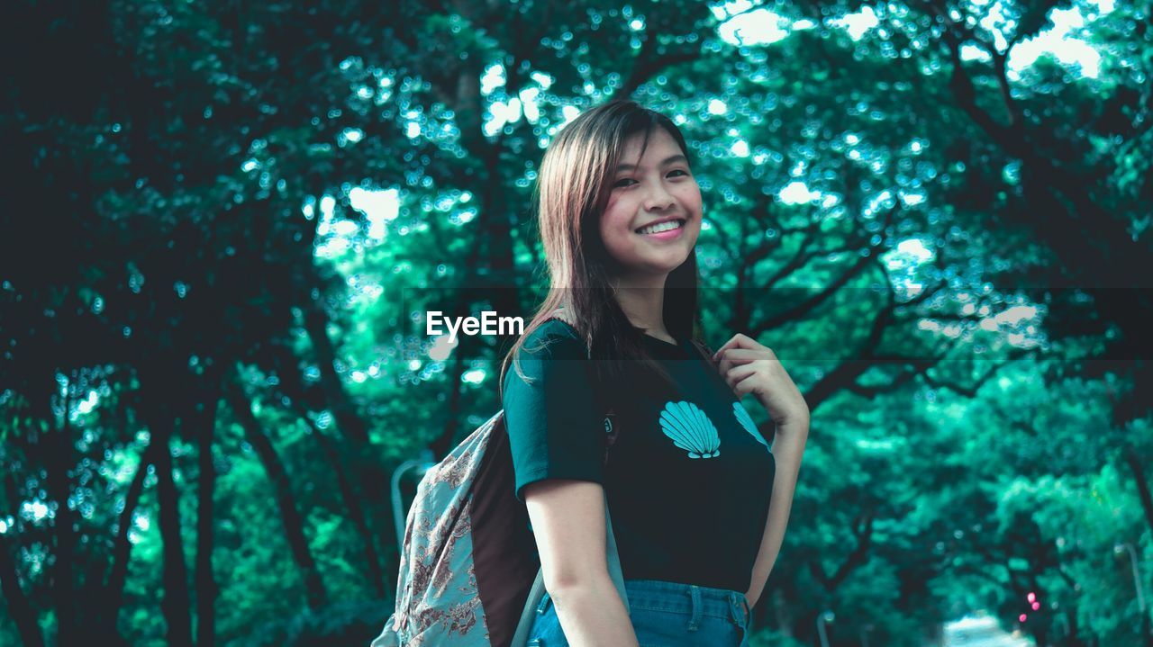 PORTRAIT OF HAPPY YOUNG WOMAN IN FOREST