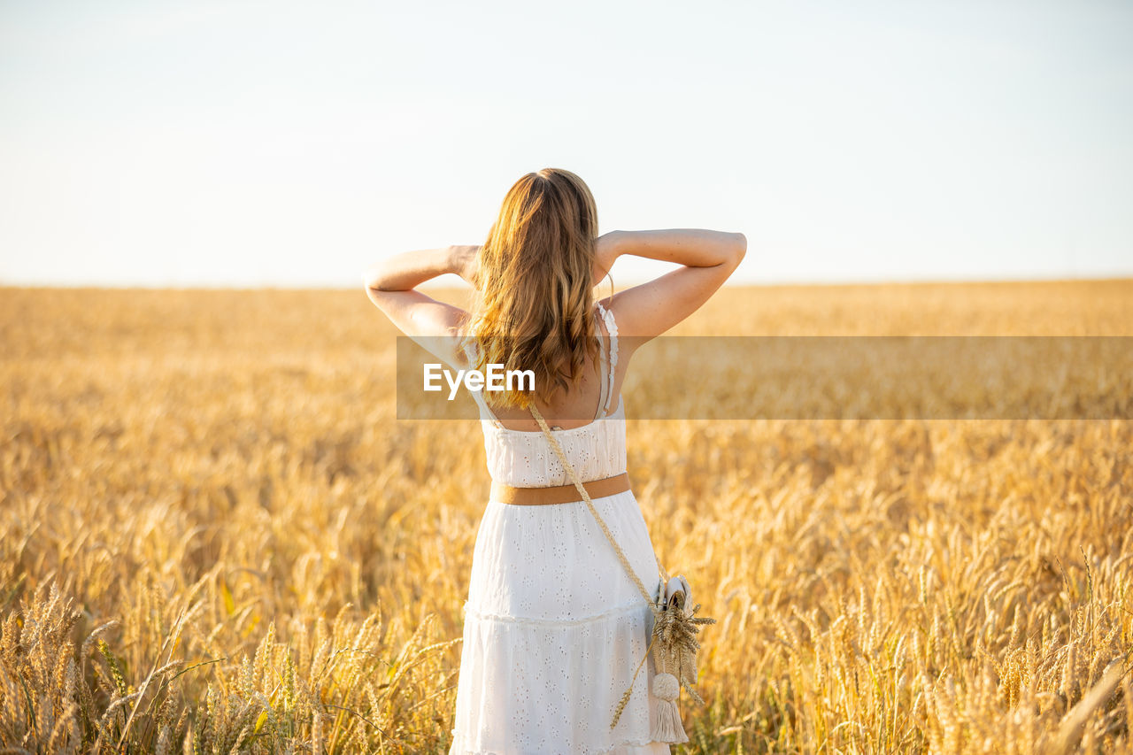 Midsection of woman standing on field against sky