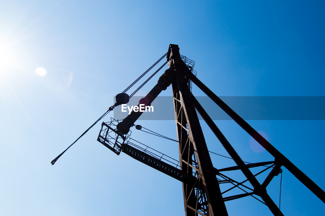 LOW ANGLE VIEW OF CRANE AGAINST BLUE SKY