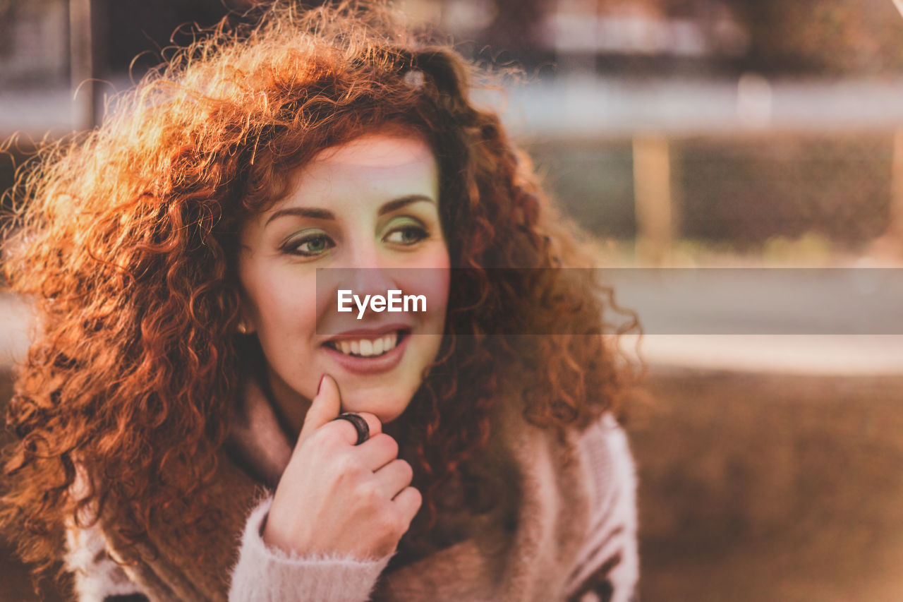 Close-up of smiling young woman with curly hair