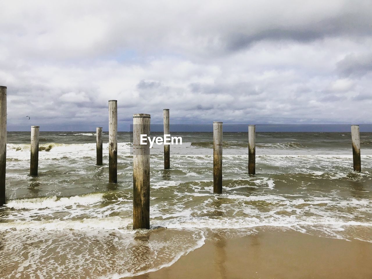 WOODEN POSTS IN SEA AGAINST SKY