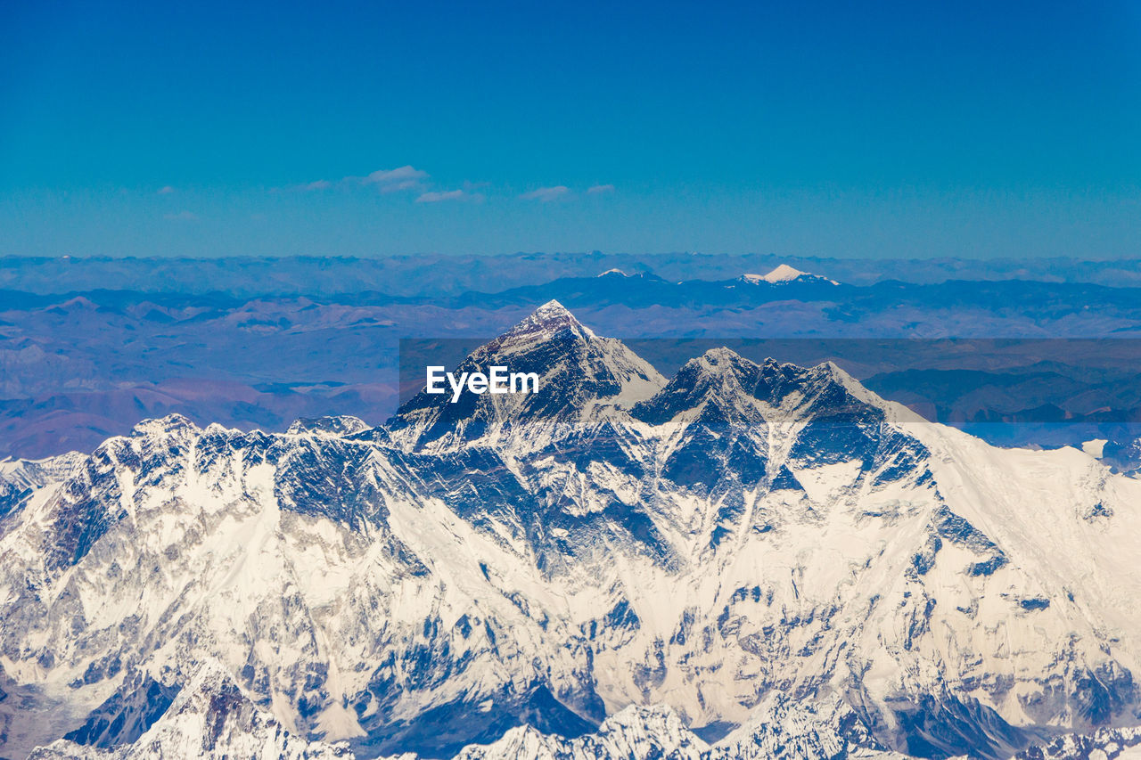Scenic view of snowcapped mountains against blue sky