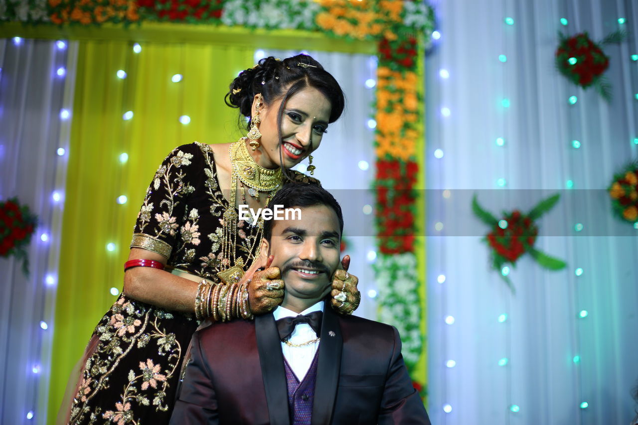 Portrait of happy bride holding groom cheeks during wedding ceremony