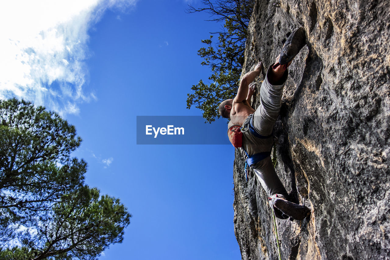 Low angle view of person on rock against sky