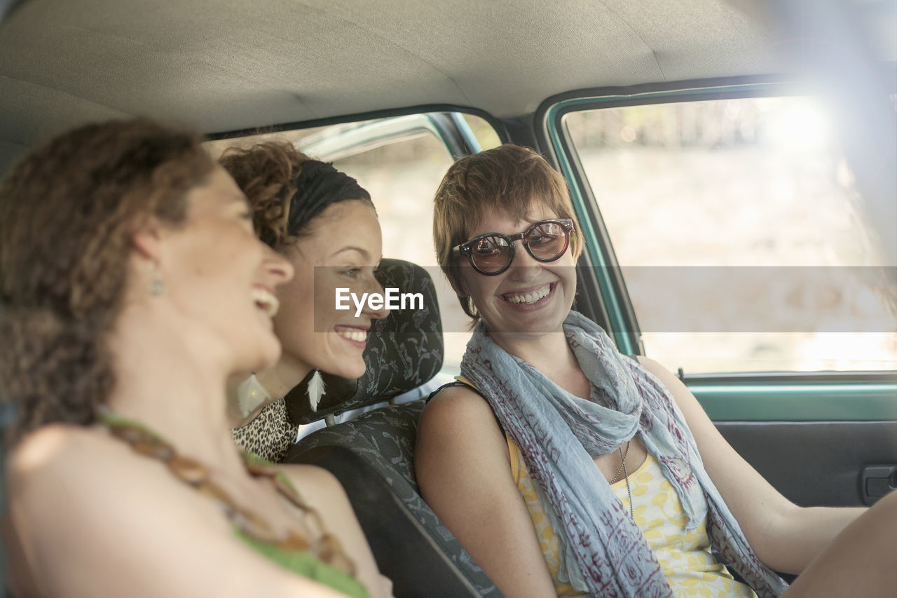 Smiling female friends sitting in car during road trip