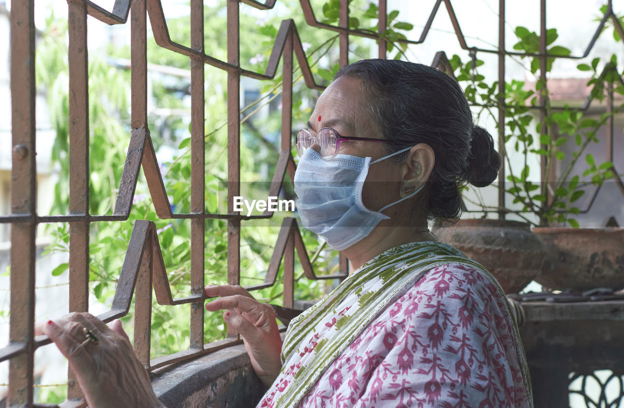 An indian woman looking outside from her house verandah. at kolkata during covid lockdown period.