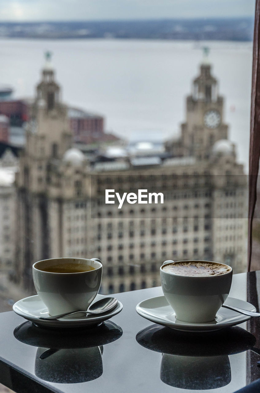 Coffee cups on table against royal liver building seen through window