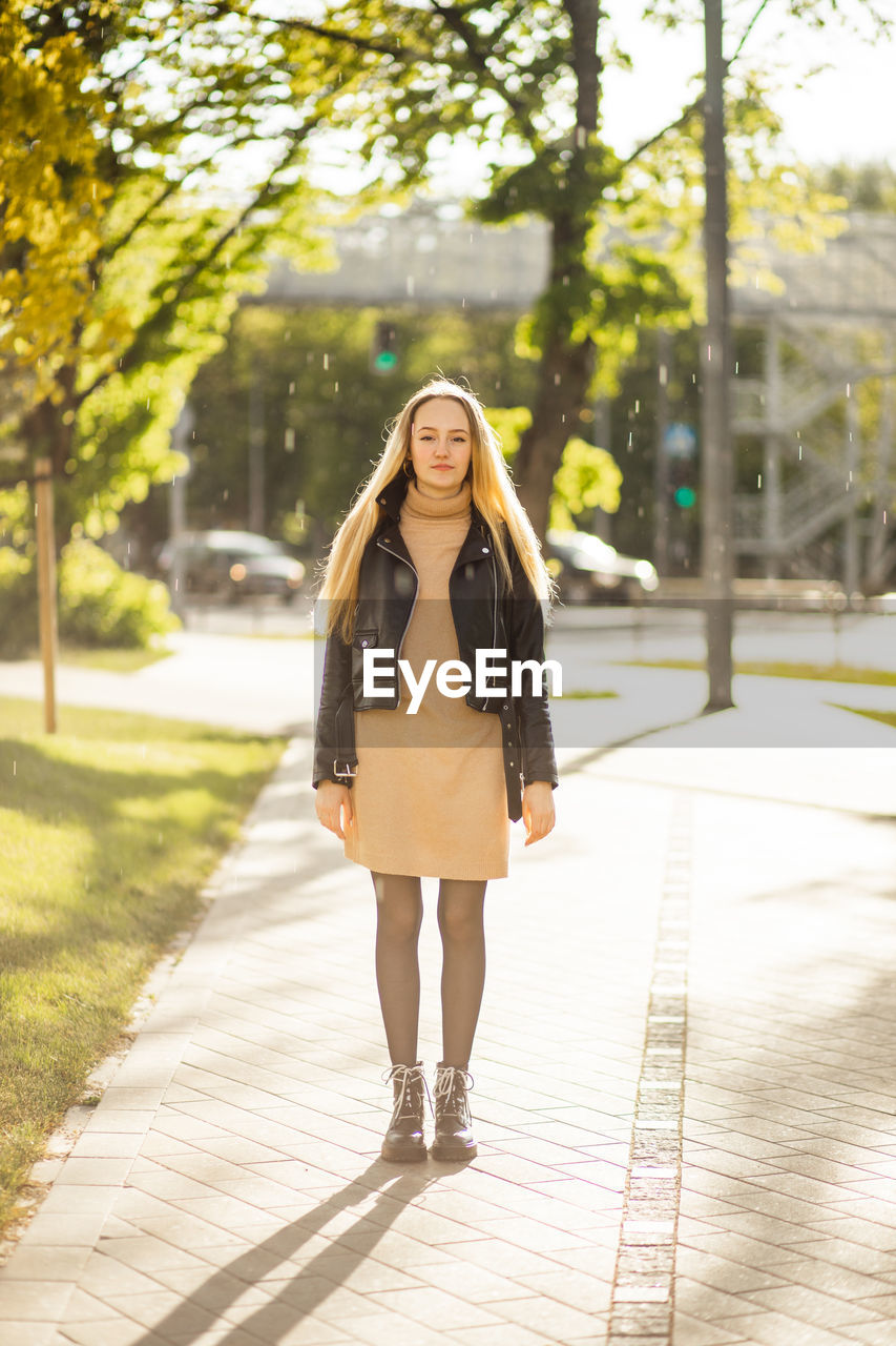 Portrait of young woman standing against trees