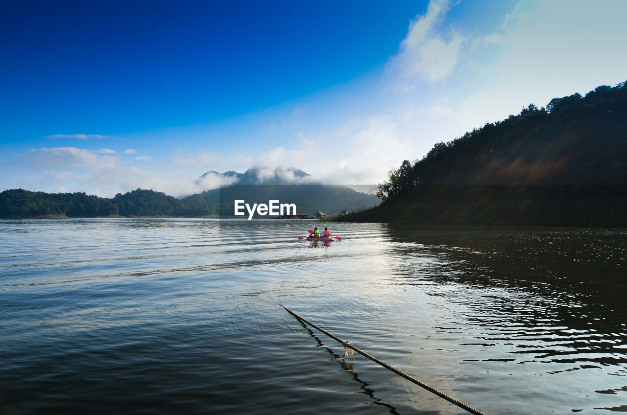 PEOPLE IN LAKE AGAINST SKY