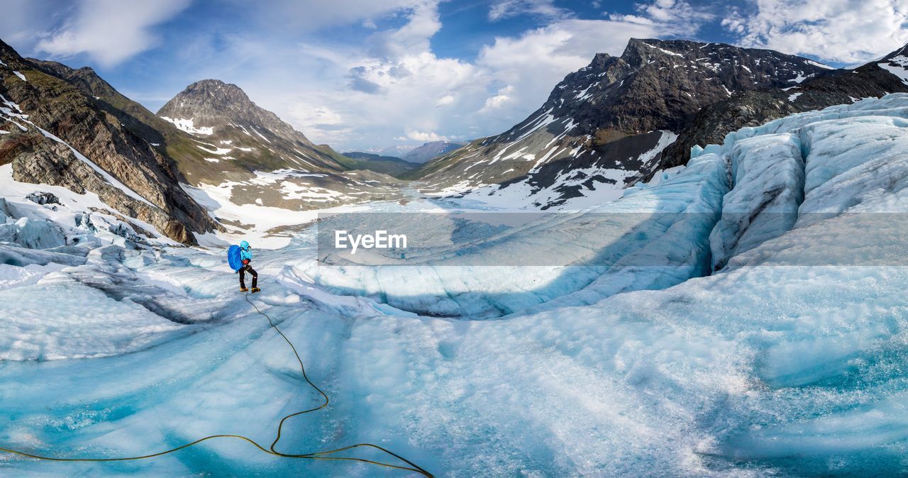 Person standing on snow covered mountains against cloudy sky