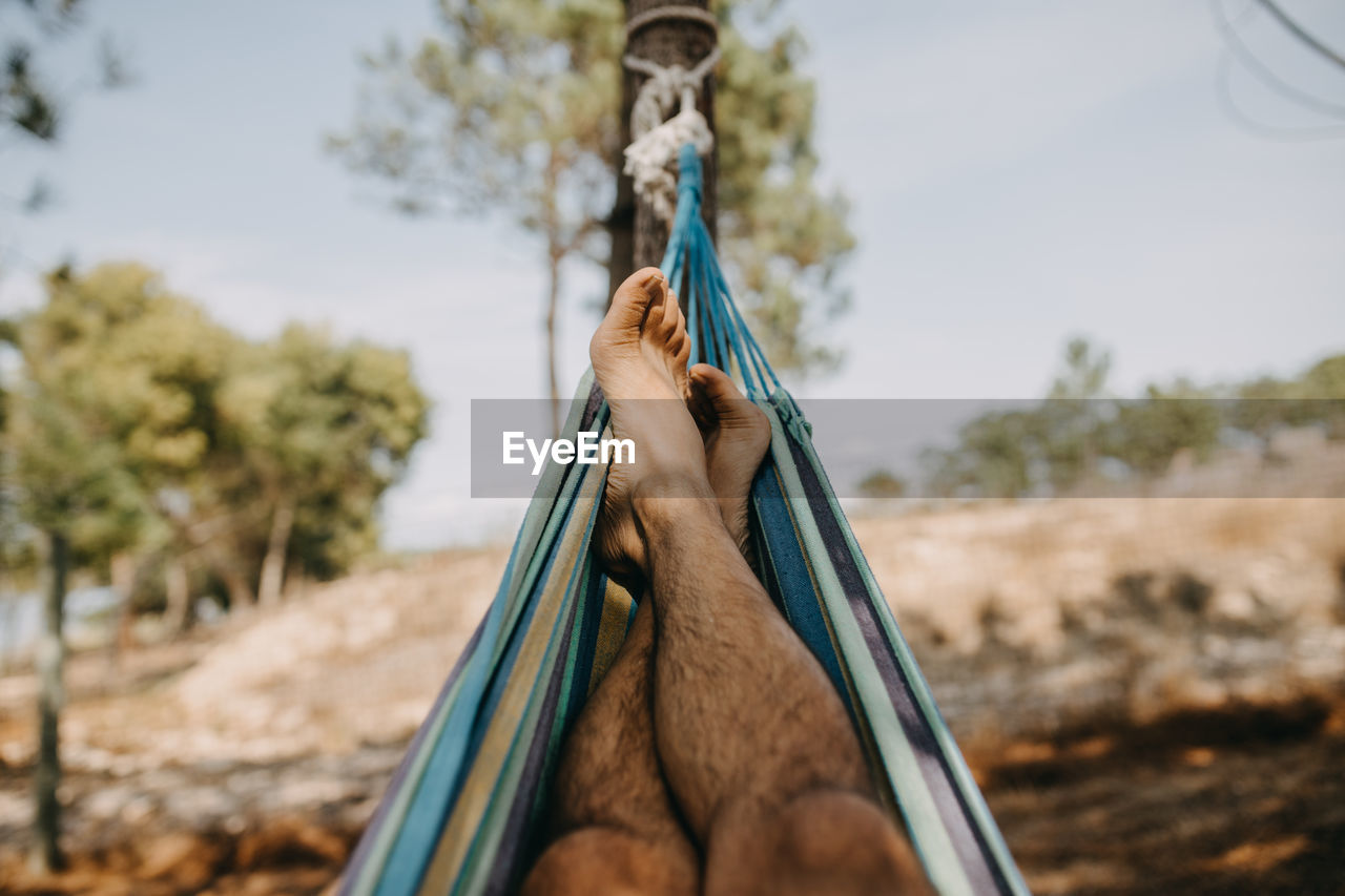 Low section of man siting on hammock outdoors