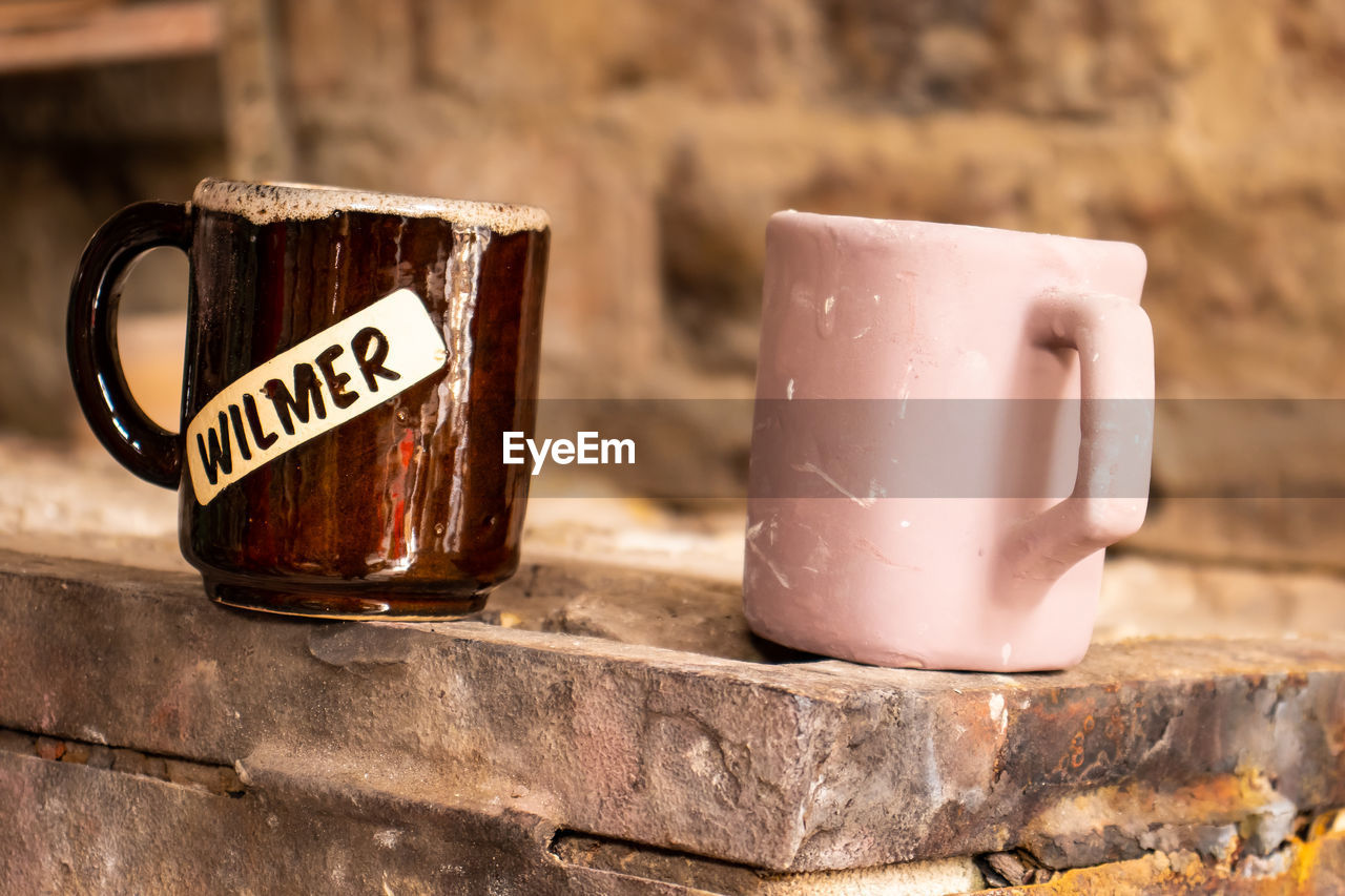 CLOSE-UP OF COFFEE CUP WITH TEXT ON TABLE