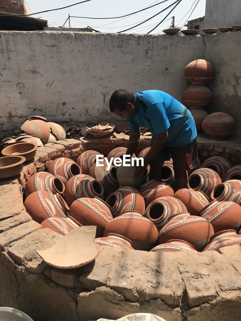 An indian traditional potter prepares water clay pots for firing.