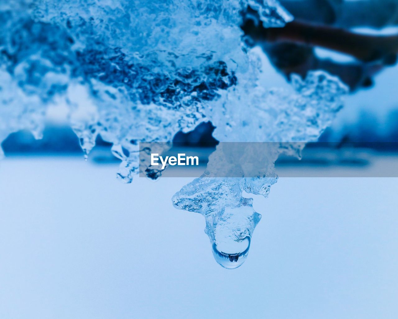 CLOSE-UP OF WATER DROP ON BLUE BACKGROUND