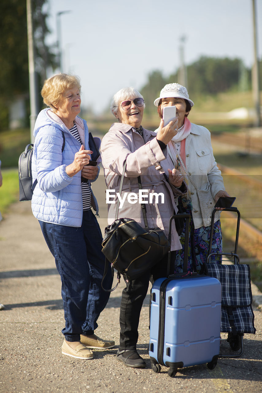 Group senior women take a self-portrait on platform  for a train to travel during covid-19 pandemic