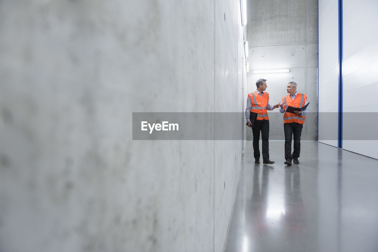 Two colleagues wearing safety vests talking